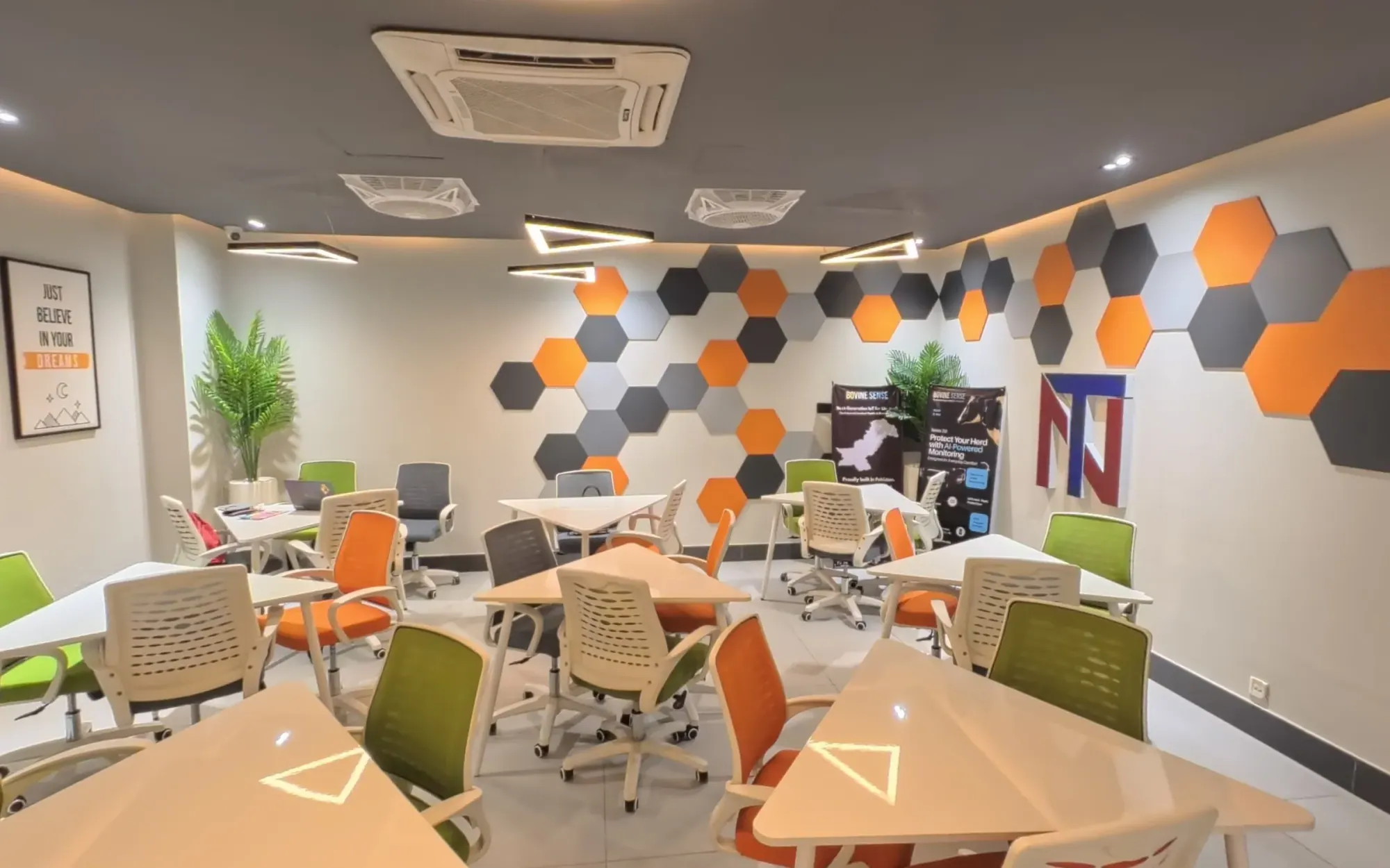 The Coworking Hall at NEIC, NUTECH Islamabad: hexagon wall panels, white desks and orange and green chairs