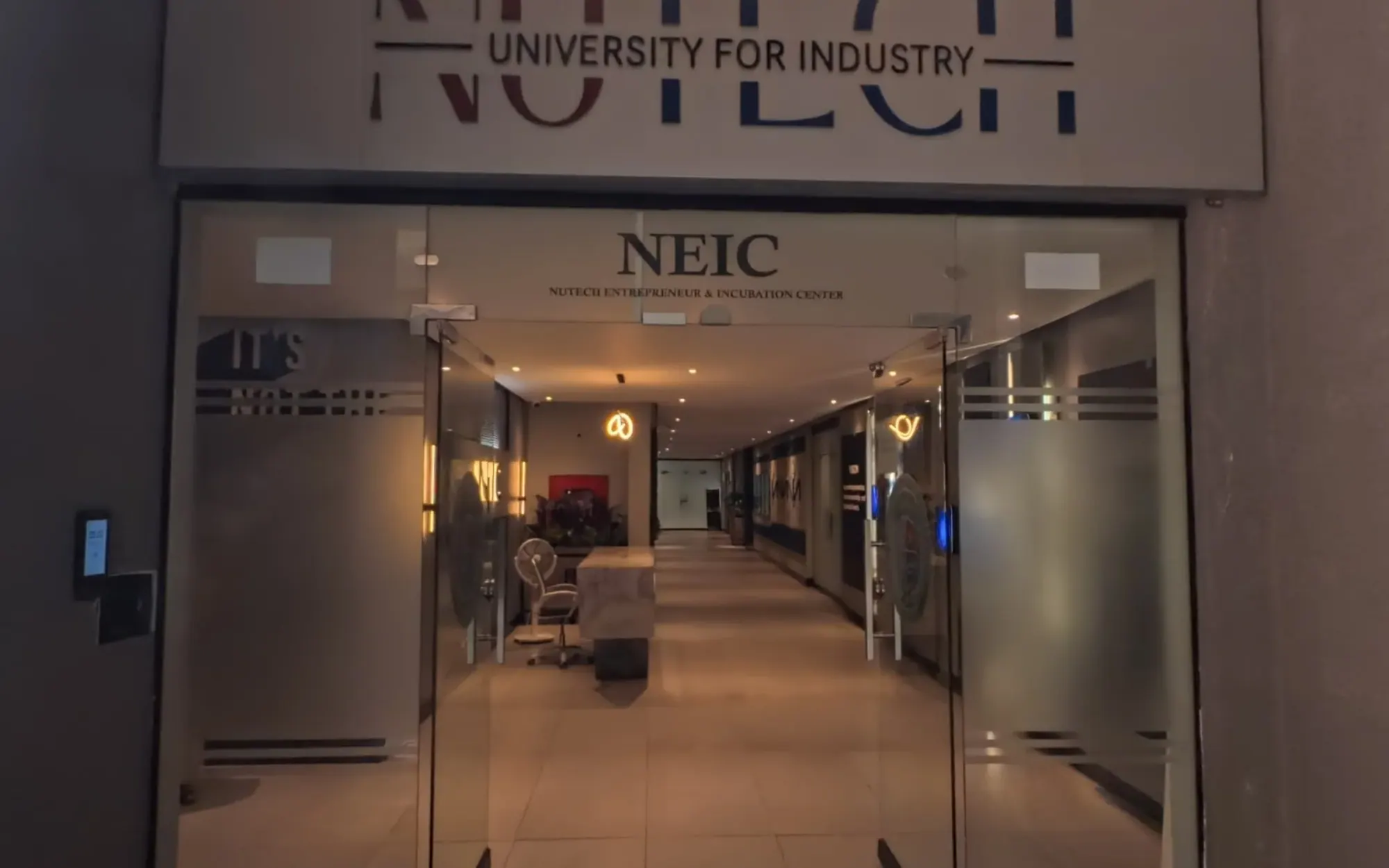 The glass entrance of NEIC under the NUTECH University for Industry sign, Islamabad